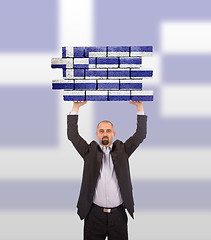 Image showing Businessman holding a large piece of a brick wall