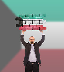 Image showing Businessman holding a large piece of a brick wall