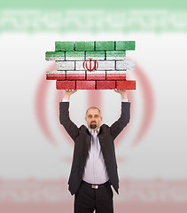 Image showing Businessman holding a large piece of a brick wall