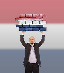 Image showing Businessman holding a large piece of a brick wall