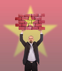 Image showing Businessman holding a large piece of a brick wall