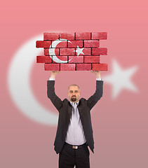 Image showing Businessman holding a large piece of a brick wall