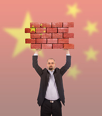 Image showing Businessman holding a large piece of a brick wall