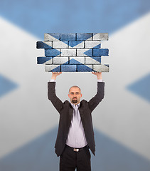 Image showing Businessman holding a large piece of a brick wall