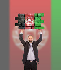 Image showing Businessman holding a large piece of a brick wall