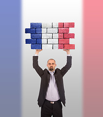 Image showing Businessman holding a large piece of a brick wall