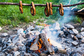 Image showing Gernan brezels on a stick over fire