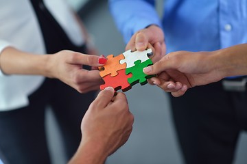 Image showing Group of business people assembling jigsaw puzzle