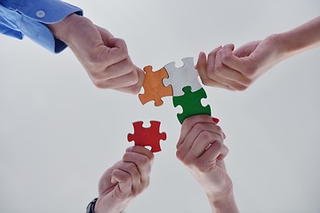 Image showing Group of business people assembling jigsaw puzzle