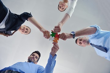 Image showing Group of business people assembling jigsaw puzzle