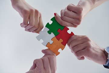 Image showing Group of business people assembling jigsaw puzzle