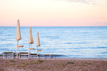 Image showing closed umbrellas on evening beach