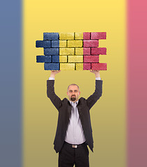 Image showing Businessman holding a large piece of a brick wall