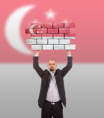 Image showing Businessman holding a large piece of a brick wall