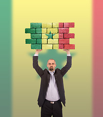 Image showing Businessman holding a large piece of a brick wall