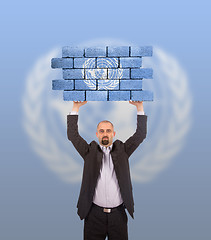 Image showing Businessman holding a large piece of a brick wall