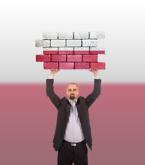 Image showing Businessman holding a large piece of a brick wall