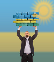 Image showing Businessman holding a large piece of a brick wall