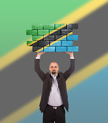 Image showing Businessman holding a large piece of a brick wall