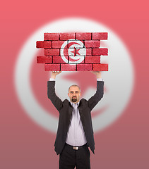 Image showing Businessman holding a large piece of a brick wall