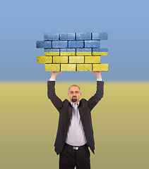 Image showing Businessman holding a large piece of a brick wall