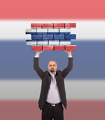 Image showing Businessman holding a large piece of a brick wall