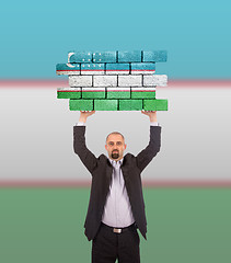 Image showing Businessman holding a large piece of a brick wall