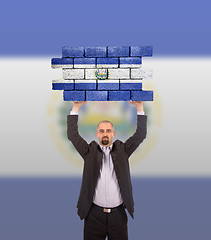 Image showing Businessman holding a large piece of a brick wall