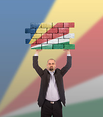 Image showing Businessman holding a large piece of a brick wall