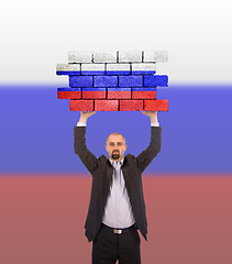 Image showing Businessman holding a large piece of a brick wall