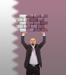 Image showing Businessman holding a large piece of a brick wall