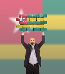 Image showing Businessman holding a large piece of a brick wall