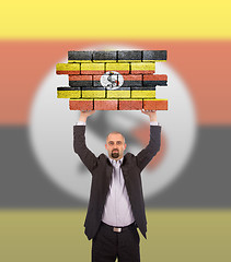 Image showing Businessman holding a large piece of a brick wall