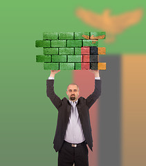 Image showing Businessman holding a large piece of a brick wall