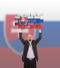 Image showing Businessman holding a large piece of a brick wall