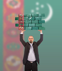 Image showing Businessman holding a large piece of a brick wall