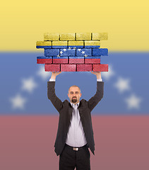 Image showing Businessman holding a large piece of a brick wall