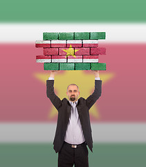 Image showing Businessman holding a large piece of a brick wall