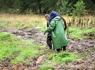 Image showing Working going to rain on a muddy road