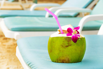 Image showing Coconut with drinking straw on beach bench