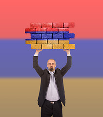 Image showing Businessman holding a large piece of a brick wall