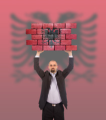 Image showing Businessman holding a large piece of a brick wall