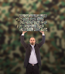 Image showing Businessman holding a large piece of a brick wall