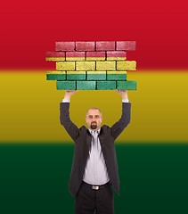 Image showing Businessman holding a large piece of a brick wall