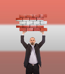 Image showing Businessman holding a large piece of a brick wall