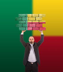 Image showing Businessman holding a large piece of a brick wall