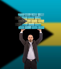 Image showing Businessman holding a large piece of a brick wall