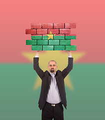 Image showing Businessman holding a large piece of a brick wall