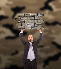 Image showing Businessman holding a large piece of a brick wall