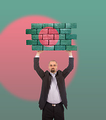 Image showing Businessman holding a large piece of a brick wall